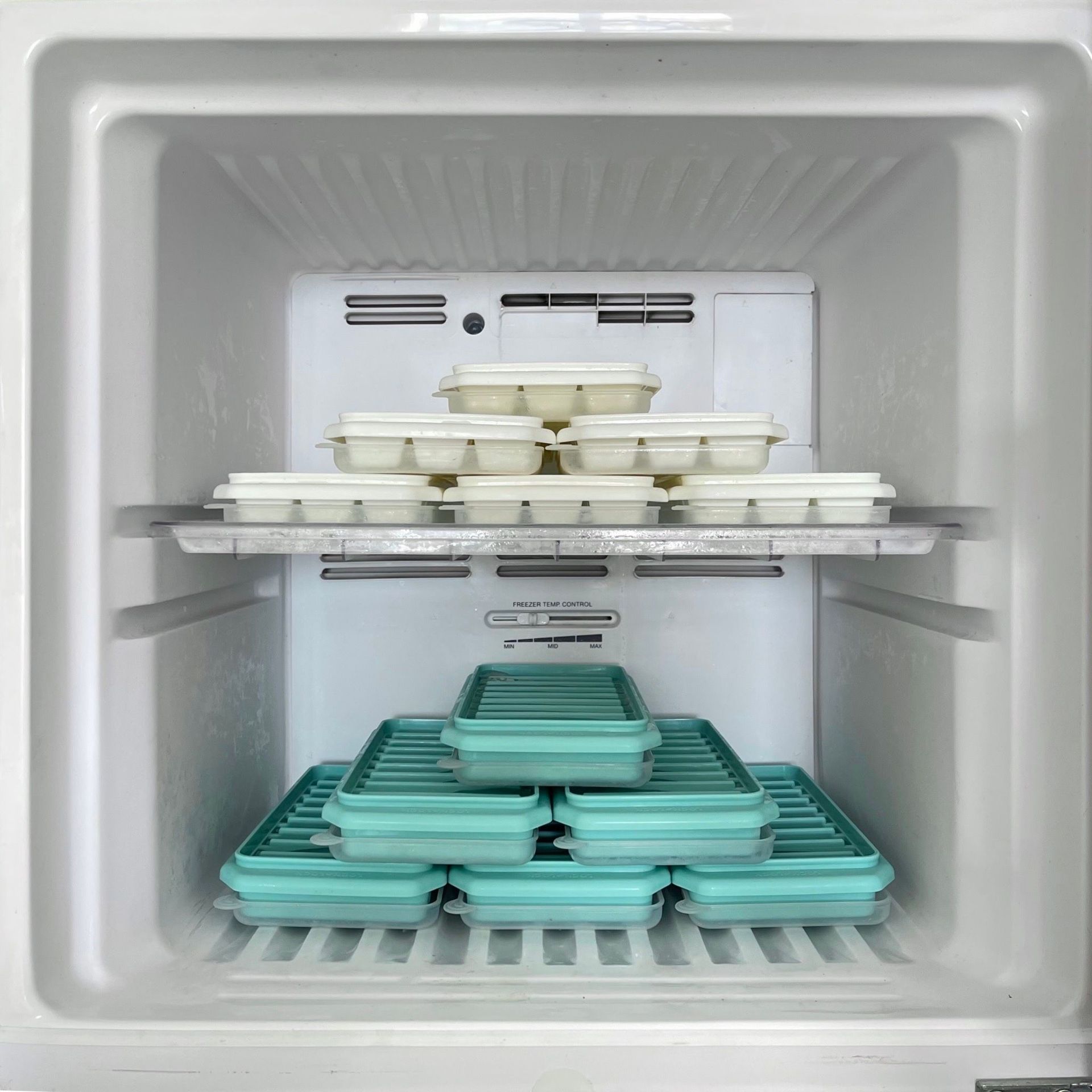 A well-arranged freezer filled with ice trays in a home kitchen setting.